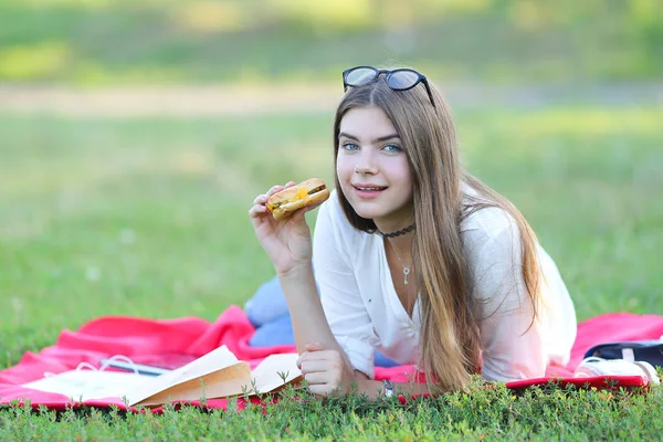 Женская работа лежа в стаканах в парке и еда закуски — стоковое фото