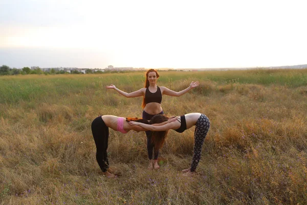Женщина практикует йогу стоя в позе, две девушки согнуты и гра — стоковое фото