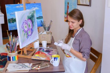 Şirin kız sanatçı tutan fırça el ve çizer, içecekler kupa,