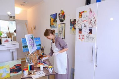 Güzel genç ressam boyalar Resim fırçaları ve petrol, kullanır ve