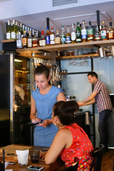 Lovely young girl waiter holds tablet and takes order communicat