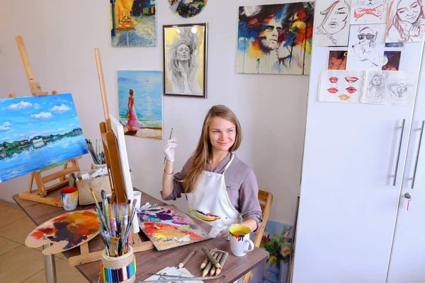 Girl Sits on Stool at Easel And Writing Painting, Uses Brush to — Stock Photo, Image