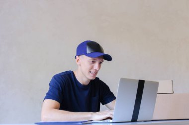 Postane bilgisayarda yazarak masada oturan kurye.