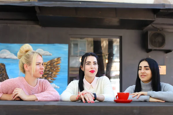 Drei schöne Frauen lächeln im Café, reden, erzählen Geheimnisse, essen, d — Stockfoto