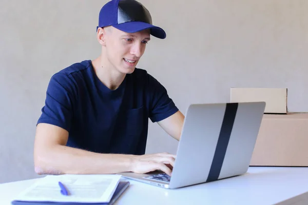 Mensajero sentado en el escritorio, escribiendo en la computadora en la oficina de correos . — Foto de Stock