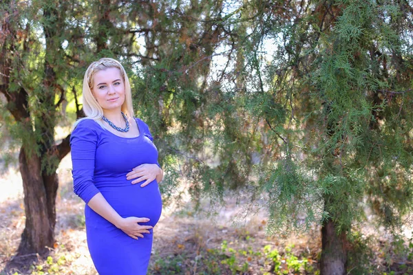 Viettelevä nuori raskaana oleva nainen hyväillä koskettaa vatsa ja tuntuu herne — kuvapankkivalokuva