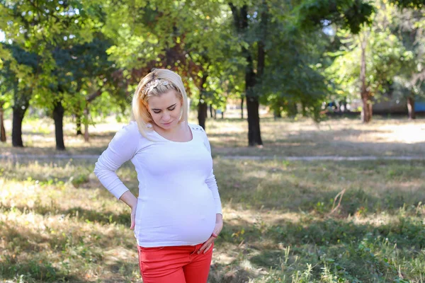 Bardzo kobiece kobieta w ciąży Blondynka delikatnie głaszcząc brzuch i uśmiechając się, — Zdjęcie stockowe