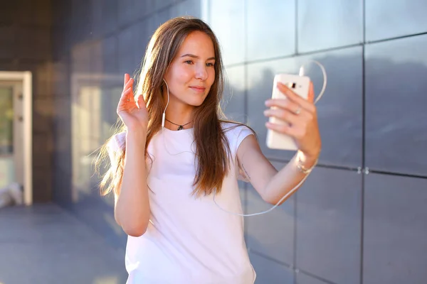 Hermosa chica joven estudiante sosteniendo el teléfono, sonriendo, ola — Foto de Stock