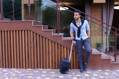 Çekici genç Arap adam elinde bavulla ayakta ve p
