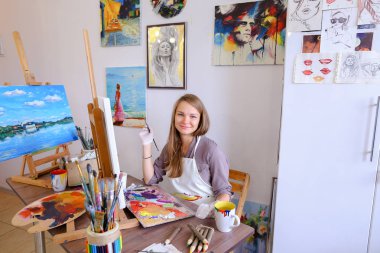 Kız şövale ve yazma boyama Stool'da oturur, fırça için kullanır