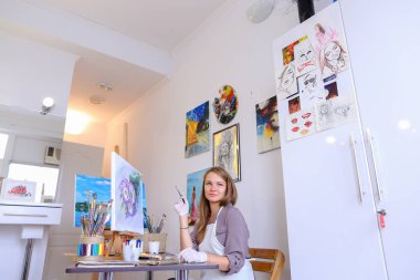 Kız şövale ve yazma boyama Stool'da oturur, fırça için kullanır