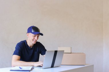 Postane bilgisayarda yazarak masada oturan kurye.