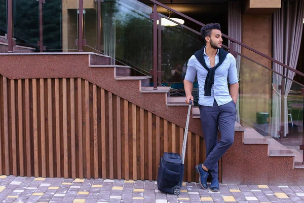 Atractivo joven árabe de pie con la maleta en la mano y p — Foto de Stock