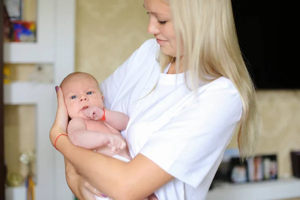 Pretty lady holds in arms and pressed to chest newborn, hugging — Stock Photo, Image