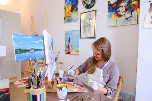 Girl Sits on Stool at Easel And Writing Painting, Uses Brush to — Stok Foto