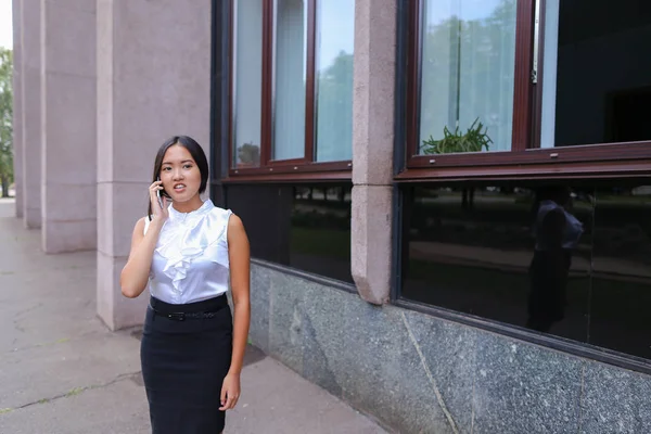 Young business woman talks on phone and smiling on background of