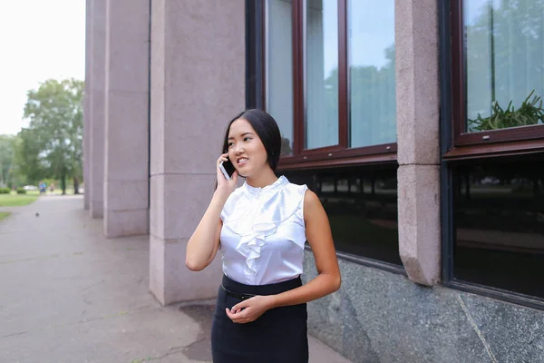 Young business woman talks on phone and smiling on background of