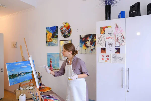 Όμορφη νεαρή ζωγράφος χρώματα εικόνα χρησιμοποιεί βούρτσες και λάδι, και — Φωτογραφία Αρχείου
