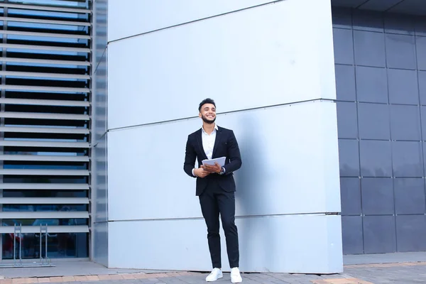 Arab fiatal üzletember mosolyogva, és tart dokumentumok közelében áll — Stock Fotó