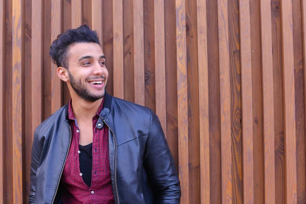 Bonito hombre árabe joven se para cerca de la pared y sonríe, Laug — Foto de Stock