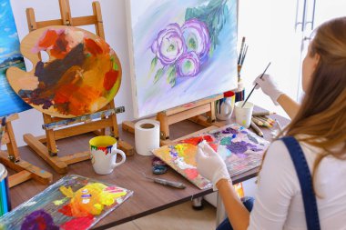 Kız sanatçı ile kamera geri oturur ve petrol resim çizer