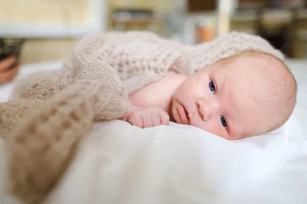 Newborn baby covered knitted blanket and lying on bed in sleepin — Stock Photo, Image