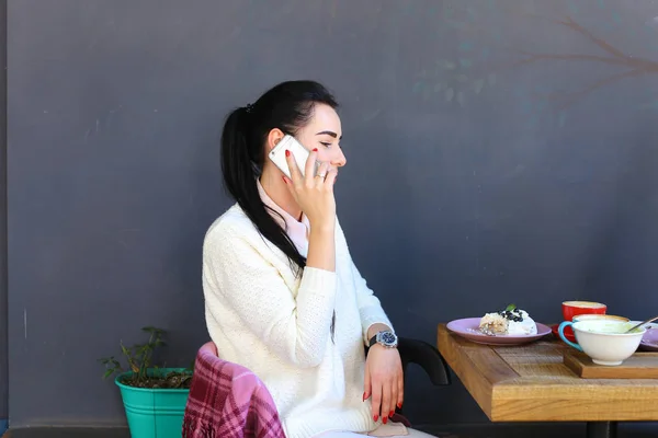 Jong meisje spreekt telefonisch, glimlachend en zitten in profiel op ch — Stockfoto