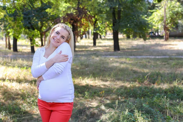 Bastante hembra embarazada rubia suavemente acariciando vientre y sonriendo , — Foto de Stock