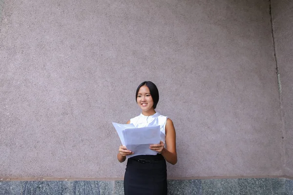Hezká dívka s úsměvem, pózování, drží papír v ruce a hledá aw — Stock fotografie