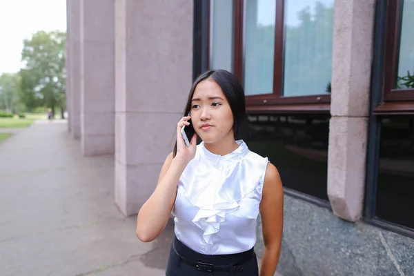 Mladí obchodních žena rozhovory o telefonu a usmívá se na pozadí — Stock fotografie