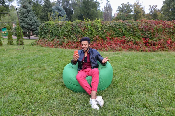 Hermoso joven árabe sostiene en las manos teléfono móvil, llamadas para arriba — Foto de Stock