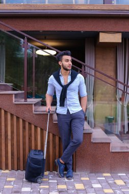 Çekici genç Arap adam elinde bavulla ayakta ve p