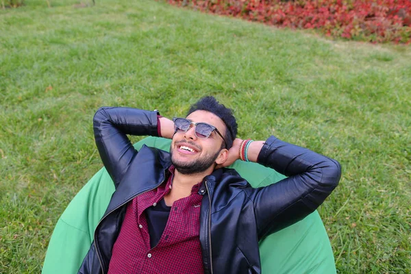 Retrato de hombre joven árabe, las mentiras de los estudiantes en la silla, sonrisa — Foto de Stock