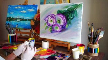 Sanatçı kız arkasında çekim. Tuval ve çiçekler Art Studio sağladığı masada oturan kadın fırçayla çizmek.