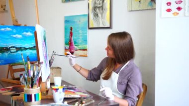 Ressam kadının son dokunuşları, yazma fırça resim ve şövale ışık Art Studio koltuğa oturan yapması.