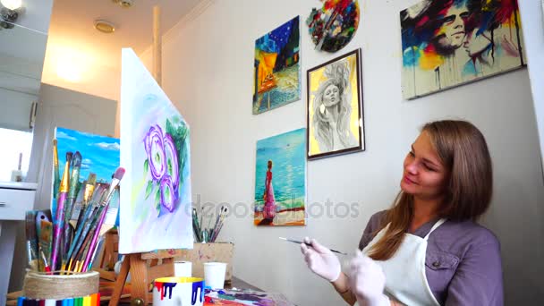 Художник дівчина сидить на станковий та фарби кисть живопису і захоплюється витвір мистецтва в світло Арт-студія. — стокове відео