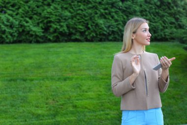 Tatlı bir sarışın telefon elinde tutan, etrafına bakıyor ve gülümsüyor bilmece