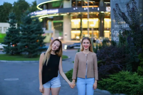 Dos muchacha encantadora de la apariencia europea tomados de la mano y sonriendo , — Foto de Stock