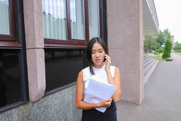 Serious young asian business woman, student talks on phone, hold