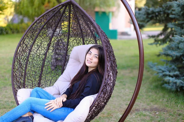 Pretty attractive woman sits comfortably in chair suspended by p