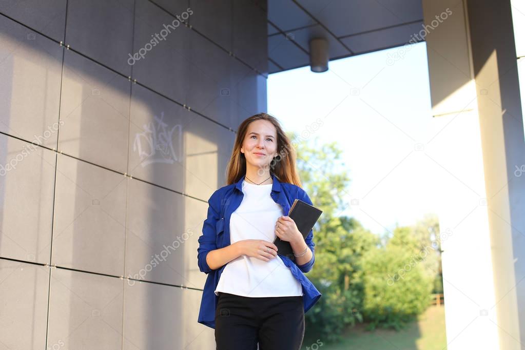 Student beautiful girl confidently goes forward and holds notebo