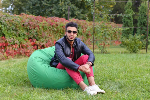 Arabe gars regarde musicalement à part et sourit, repos et assis dans — Photo