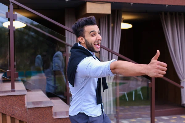 Joven alegre se ve musulmán sonriendo y mostrando gesto de mano — Foto de Stock