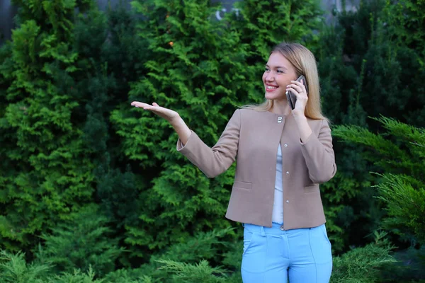 Aantrekkelijke blonde dame praten over telefoon en houdt het in de hand, smi — Stockfoto