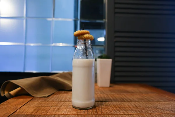 Glassflaske med melk, blomst i vase og myr drapering på bord ag – stockfoto