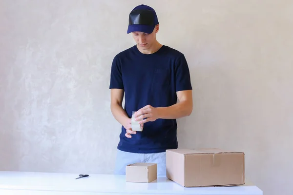 Young Man Glue Tape Box And Takes Parcel in Hands, Standing in P — Stock Photo, Image