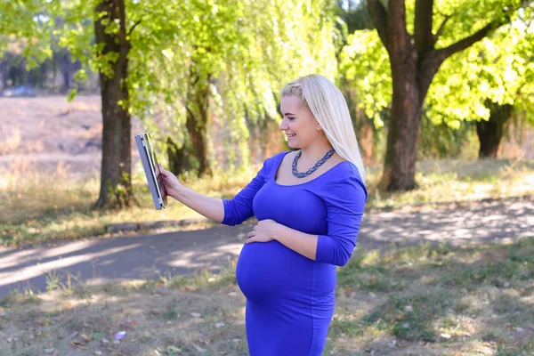 Menina grávida de boa aparência segura tablet e fala no Skype, Welc — Fotografia de Stock