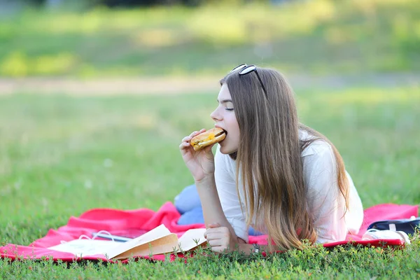 Женская работа лежа в стаканах в парке и еда закуски — стоковое фото