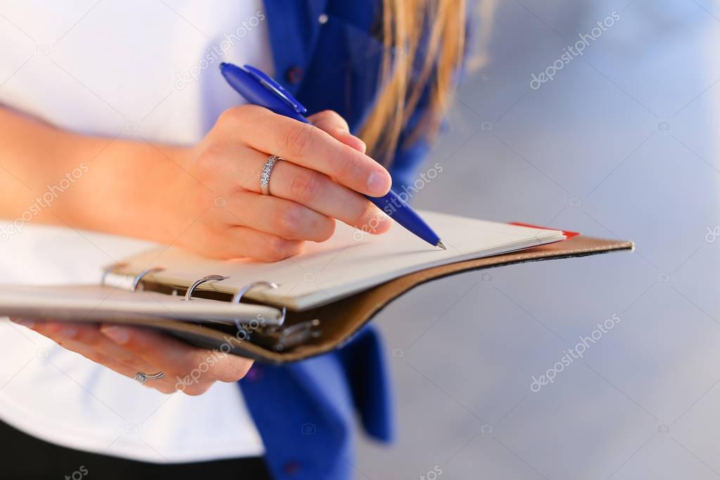 Girl holds in hands diary, notebook with sheets and pen and writ