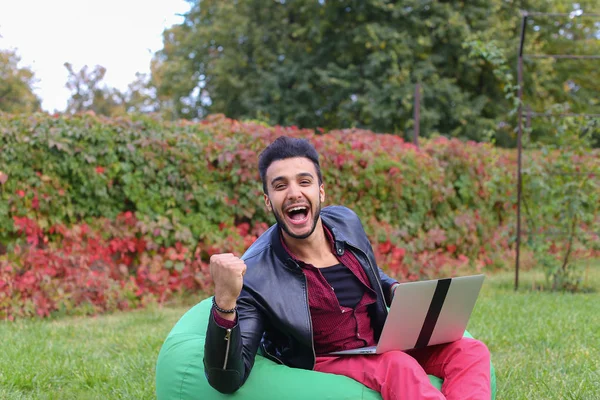 Il giovane uomo d'affari arabo riuscito si siede con il computer portatile nella sedia, S — Foto Stock